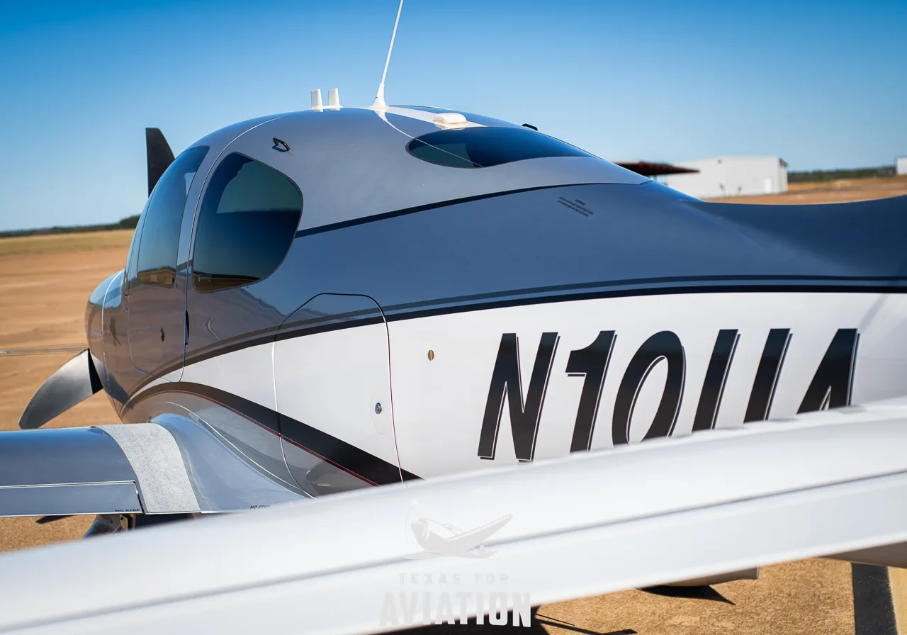 Rear-left view of the fuselage and tail of a silver and white Cirrus SR22 aircraft (N10UA).