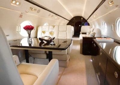 Luxurious aircraft interior with cream-colored seats and a table set for dining.