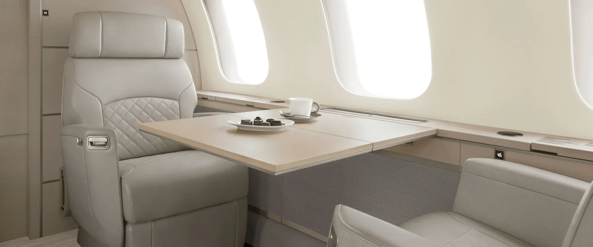Aircraft cabin with leather seat and table with snacks.