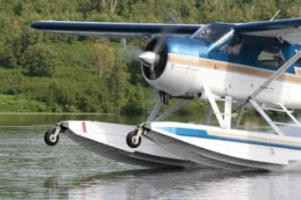Front view of a float plane on a lake with mountains in the background.