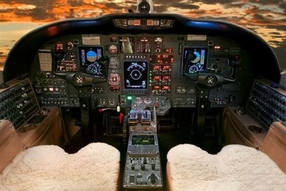 Aircraft cockpit with instrument panel and sheepskin seat covers.