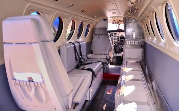 The interior cabin of an aircraft with light grey seats and a view towards the cockpit.