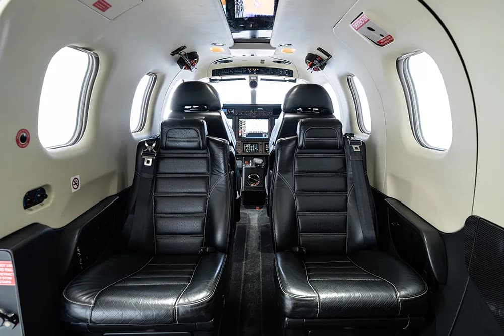 Interior view of the aircraft cabin with black leather seats facing the cockpit.