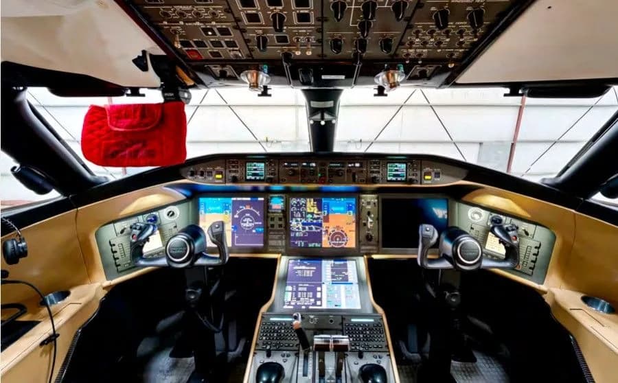The modern cockpit of a business jet, featuring multiple digital displays and a complex overhead panel.