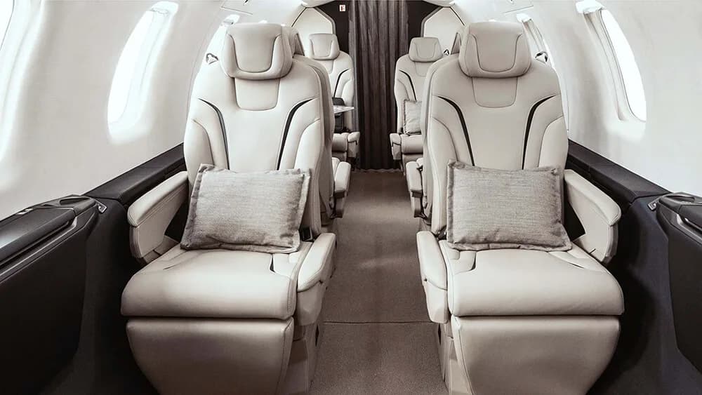 Interior view of the aircraft cabin with cream-colored leather seats and dark wood trim.