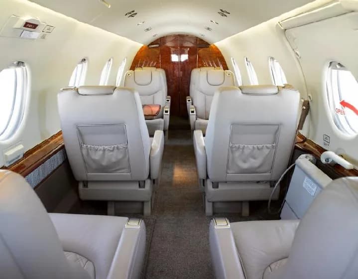 View of the Hawker 400XP cabin interior with leather seats and wood trim.