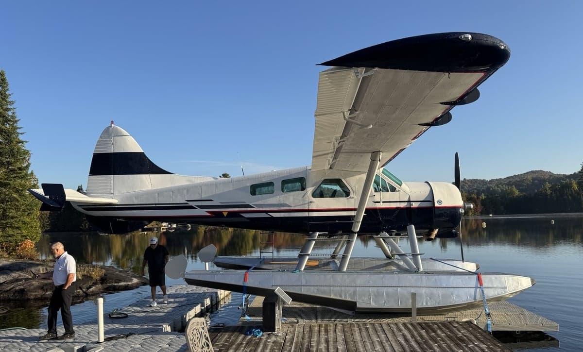 A de Havilland Canada DHC-3 Otter floatplane is docked on a lake.