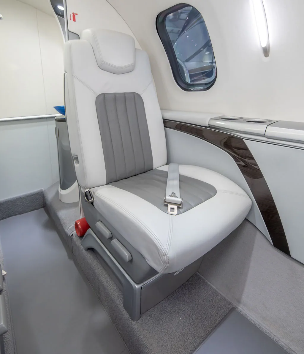 A detailed view of a white and grey leather passenger seat with a seatbelt in the HondaJet HA-420 cabin.