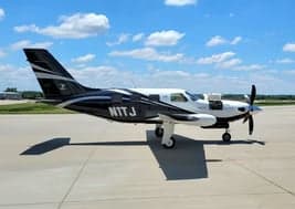 Side view of the black and white Pilatus PC-12, registration N1TJ, on the tarmac.