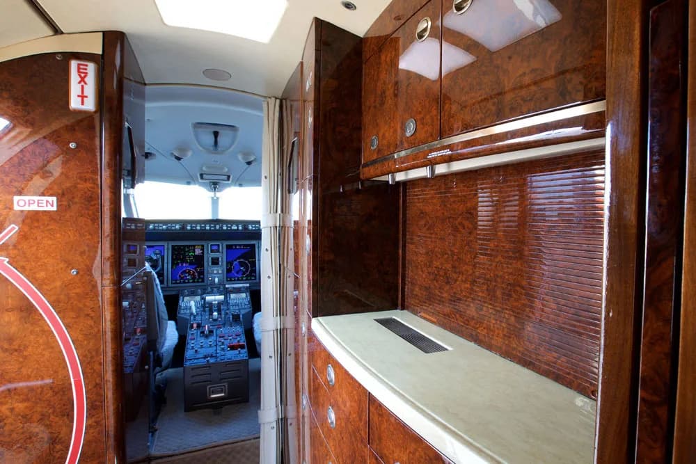 View of the aircraft interior showing the cockpit and wood cabinetry with storage and appliances.