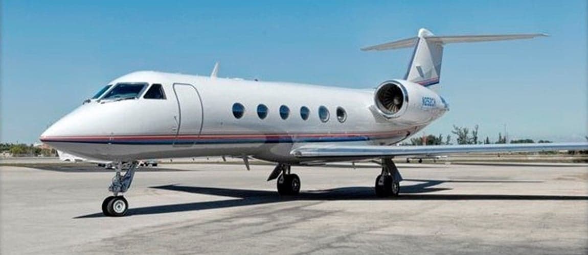 Gulfstream G-IV on the tarmac with a white paint scheme and blue and red stripes.