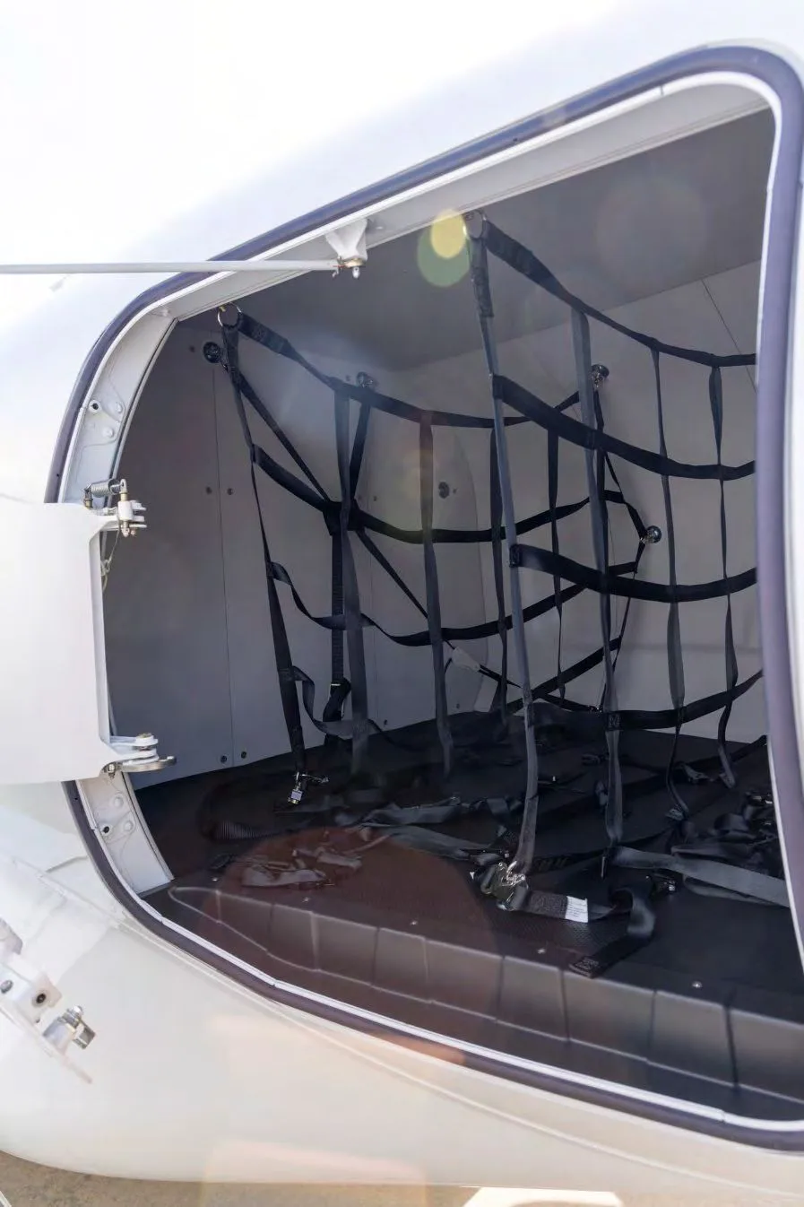 An open baggage compartment of a HondaJet Elite S, showing a cargo net inside.