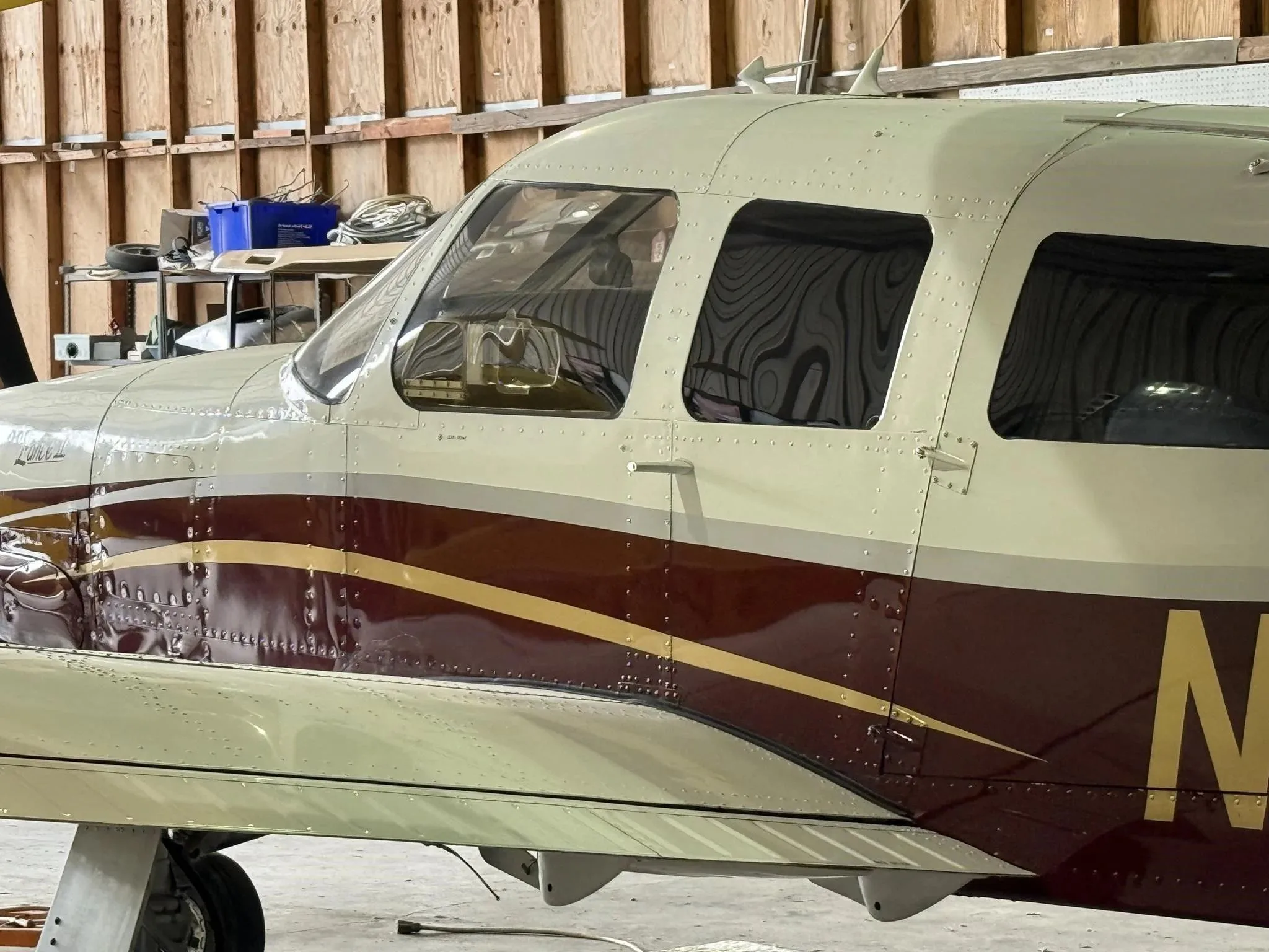 A close-up of the cockpit and cabin windows of the Piper Lance II aircraft, showing its white and maroon paint.