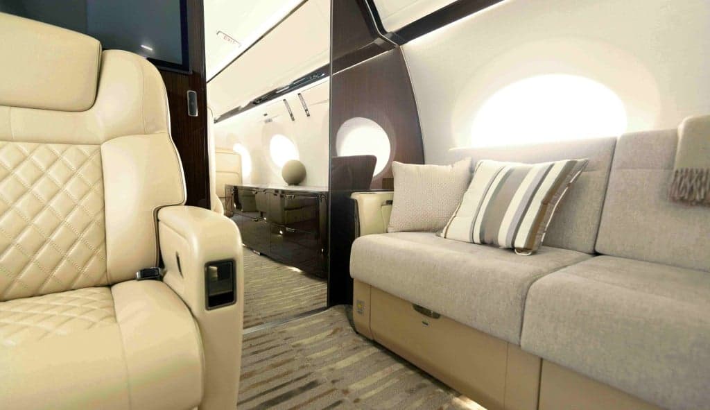 The aircraft's interior features cream-colored leather seats, wood accents, and a monitor displaying the Jety logo.