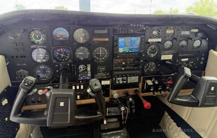 The cockpit instrument panel of a small aircraft, featuring analog gauges, two digital displays, and control yokes.