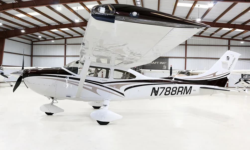 A white and brown Cessna Skylane N788RM is parked in a hangar, viewed from the side.