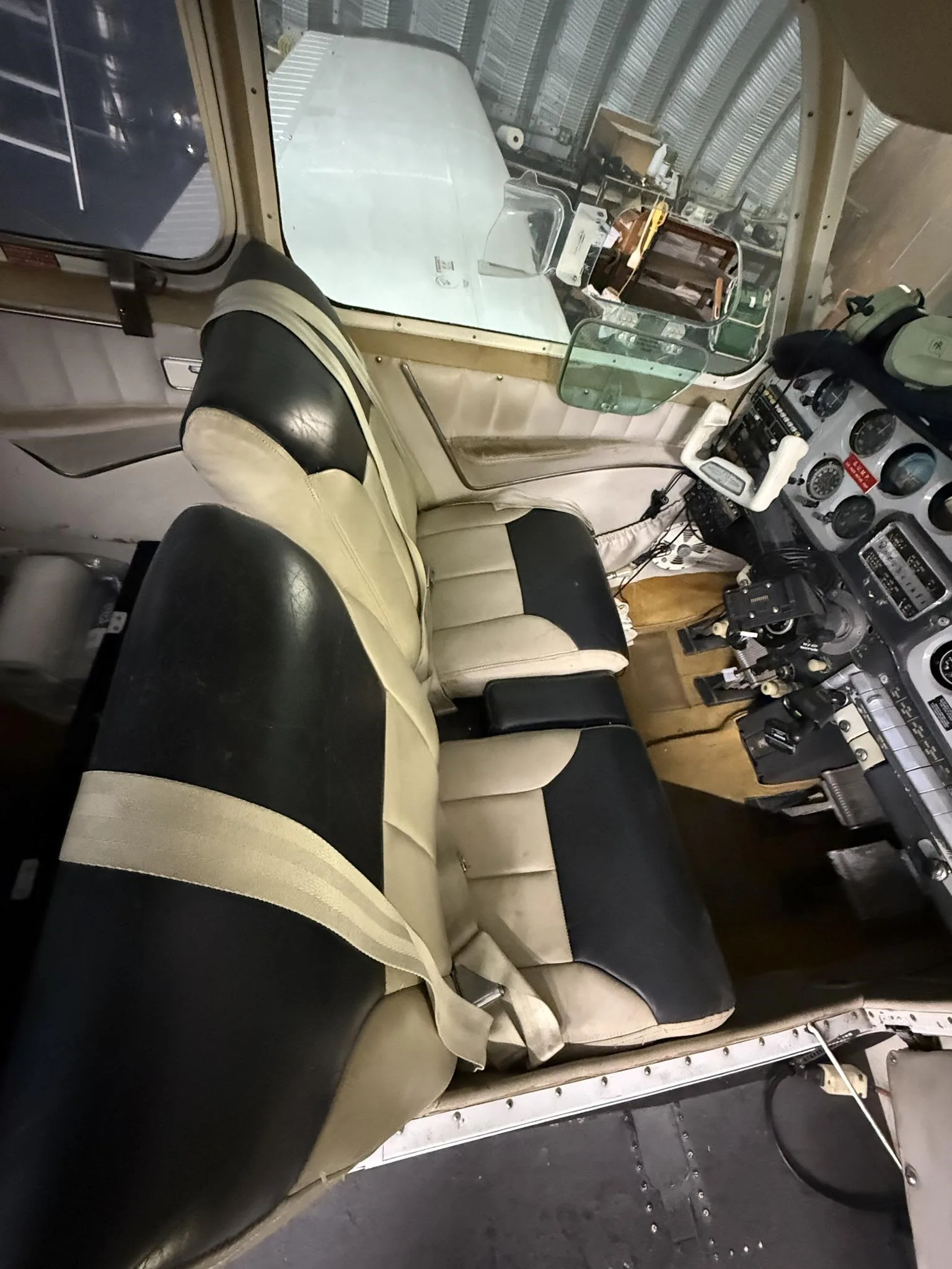 The aircraft's interior showing two-tone black and tan seats and a partial view of the cockpit.