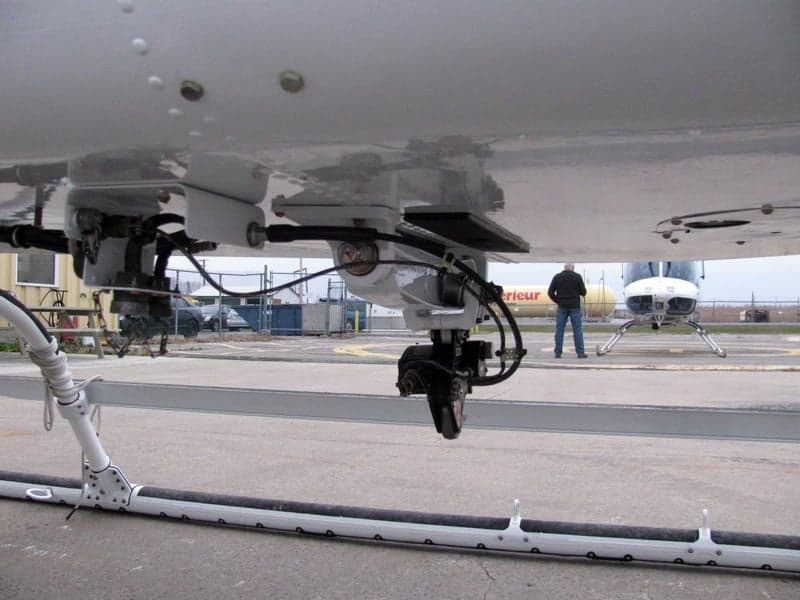 Underside view of a Bell 407 helicopter with mounted equipment.