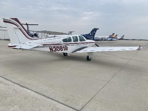A Beechcraft Bonanza with tail number N30819 parked on the ramp with other aircraft in the background.