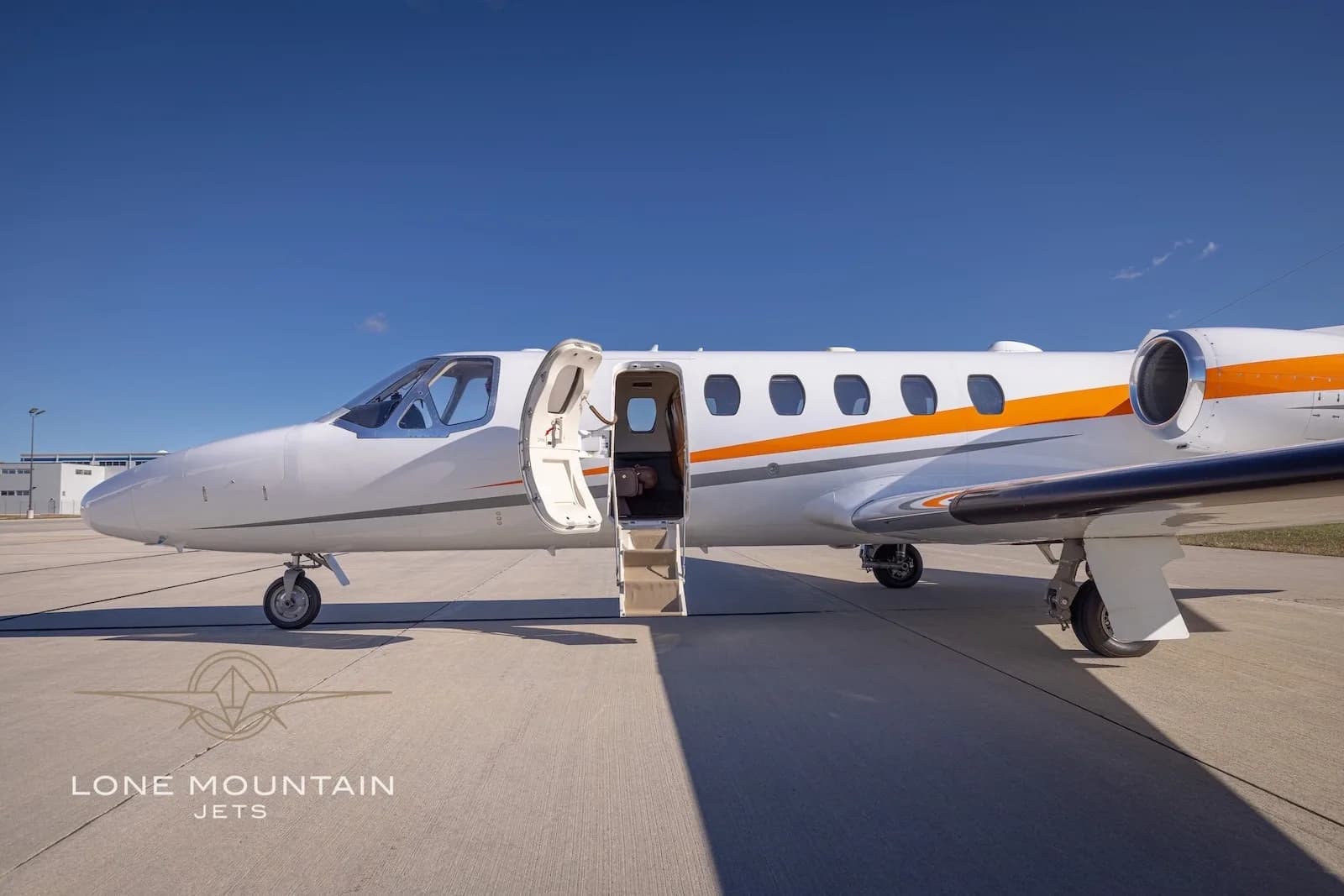 A side view of the white Cessna Citation Bravo business jet N589HH with its main cabin door open and stairs extended.
