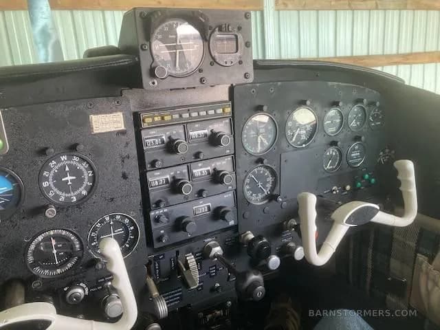 The aircraft's cockpit features a black instrument panel with various gauges, radios, and white control yokes.