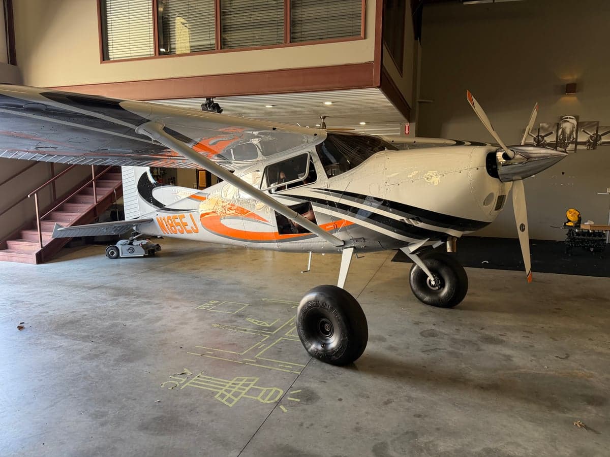 Front view of the N185EJ Cessna 185 on the ground inside a hangar.