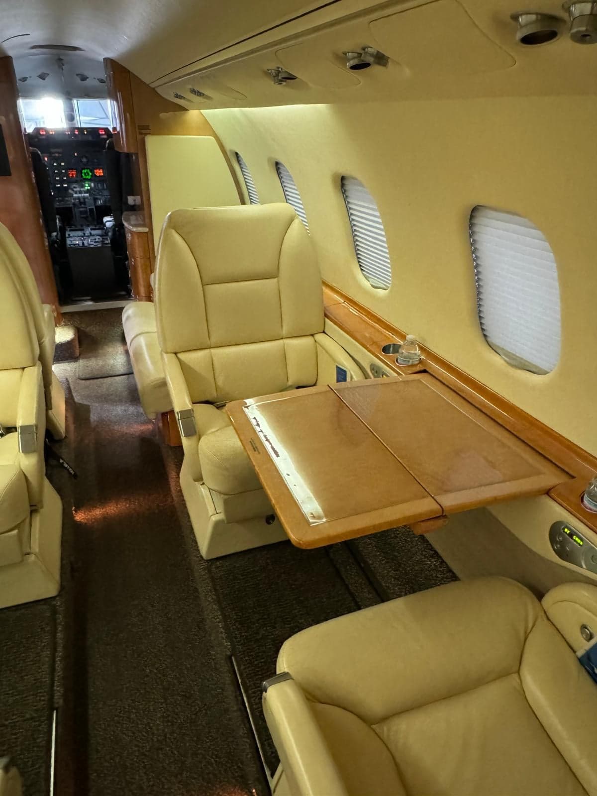 Interior view of the aircraft cabin with leather seats and a wooden table.