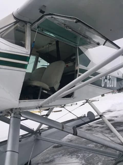 The open door of a white and green aircraft, C-GZUW, reveals the interior.