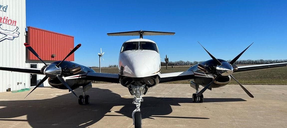 Front view of a Beechcraft King Air with a black and white paint scheme parked on the tarmac.