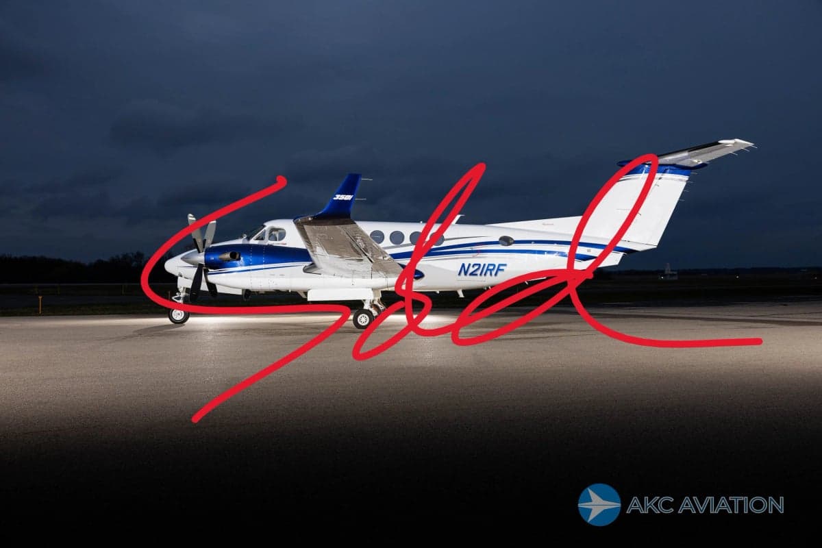 A Beechcraft King Air 350i aircraft with a blue and white paint scheme is parked on the tarmac at night.