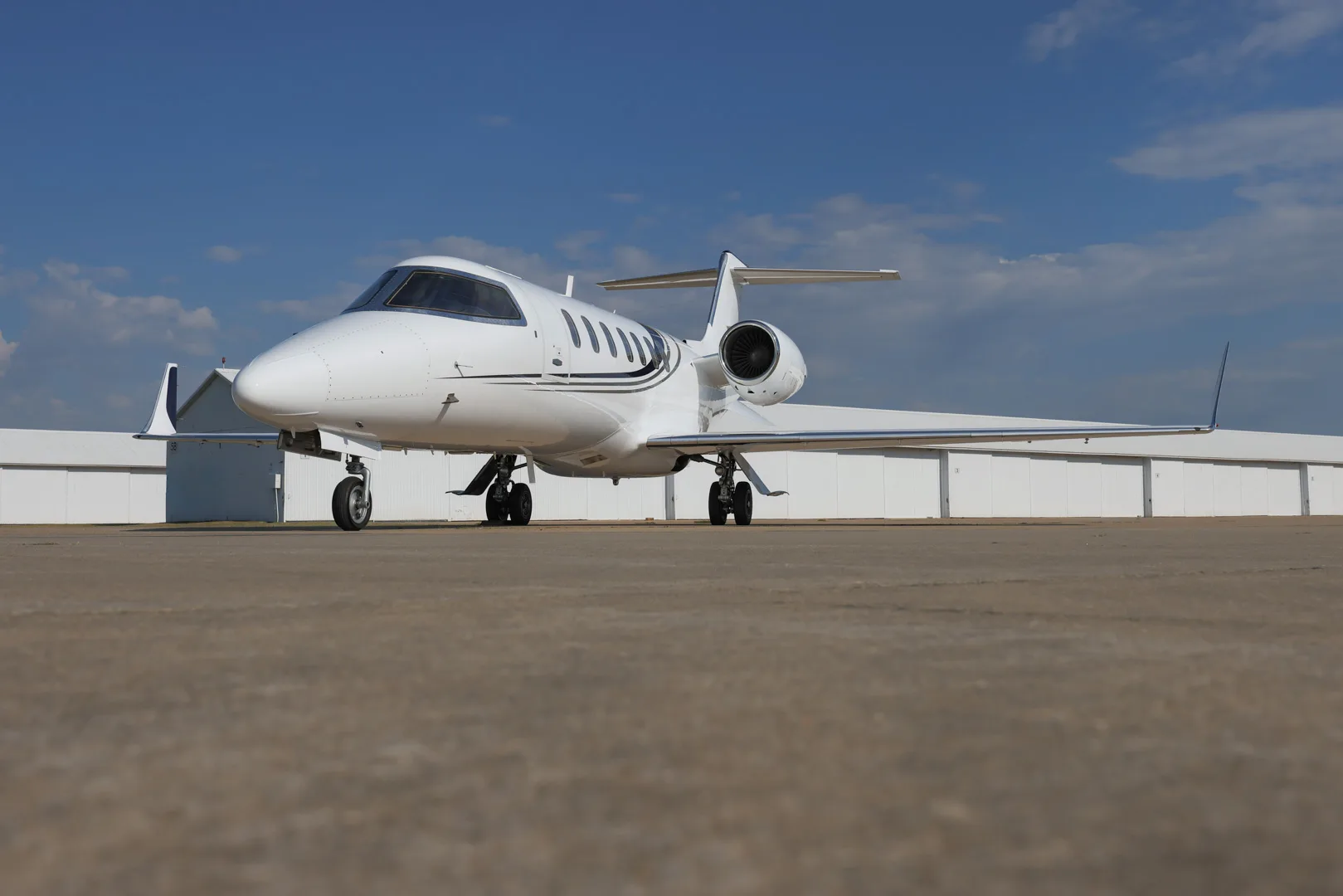 Front quarter view of the white jet N711BH on the tarmac.