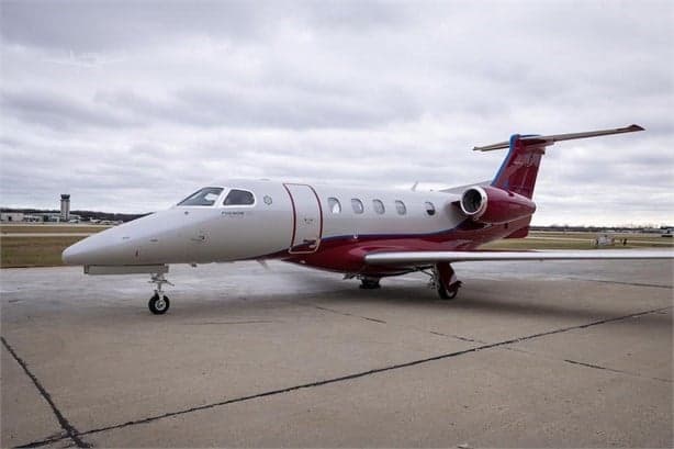 A Phenom 300E aircraft is parked on the tarmac.