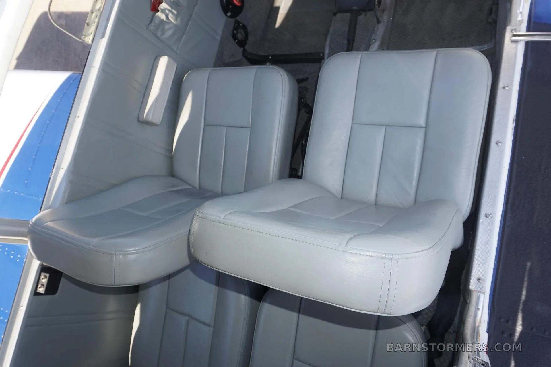 Two light gray leather aircraft seats are visible in the cabin, with a blue stripe on the exterior wall.