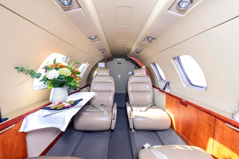 Interior of the aircraft with leather seats and a table with flowers.