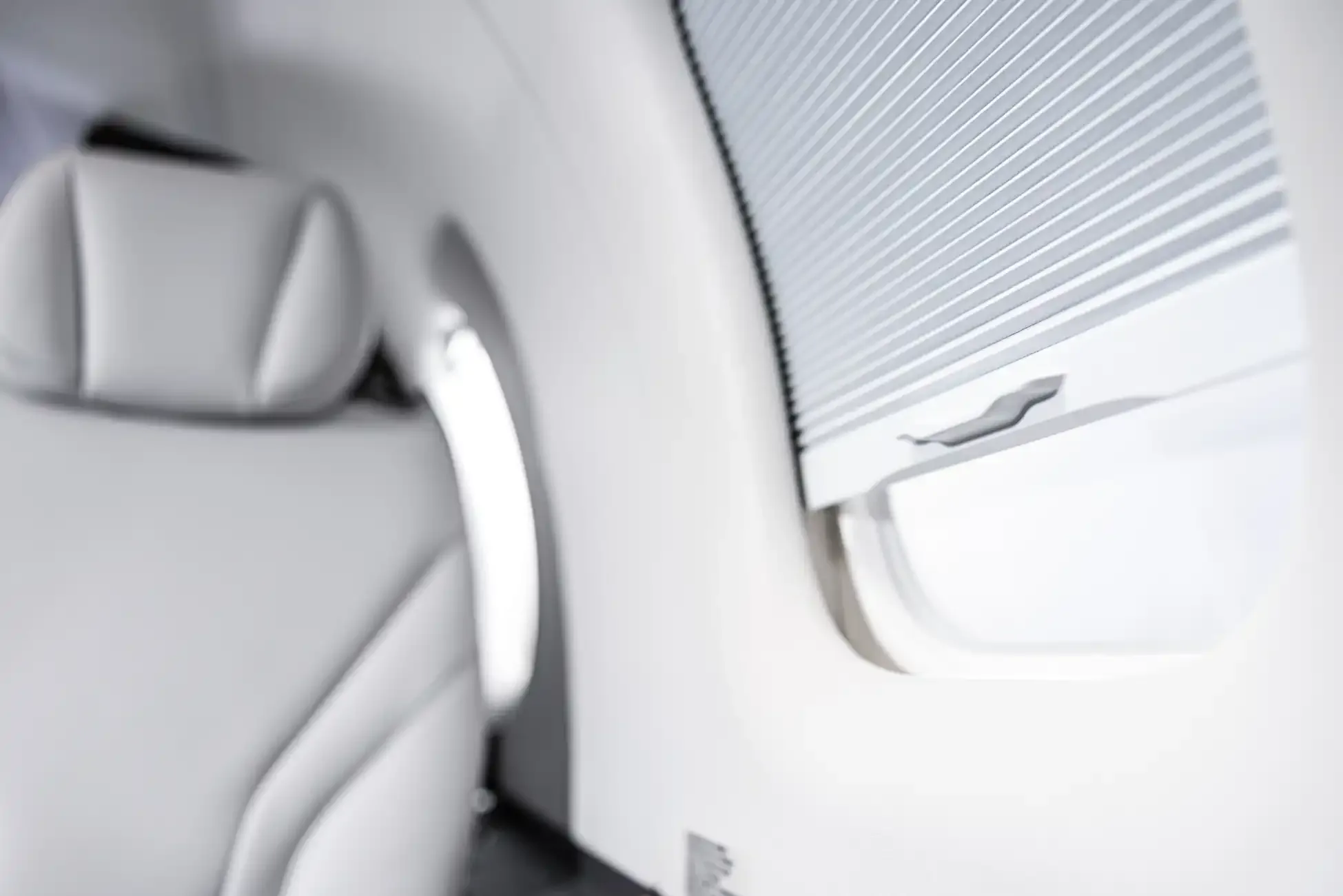 Close-up of the aircraft's interior showing a white leather seat and window with a shade.