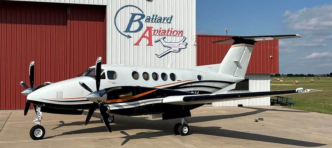 King Air aircraft parked in front of a hangar with a black and white paint scheme.