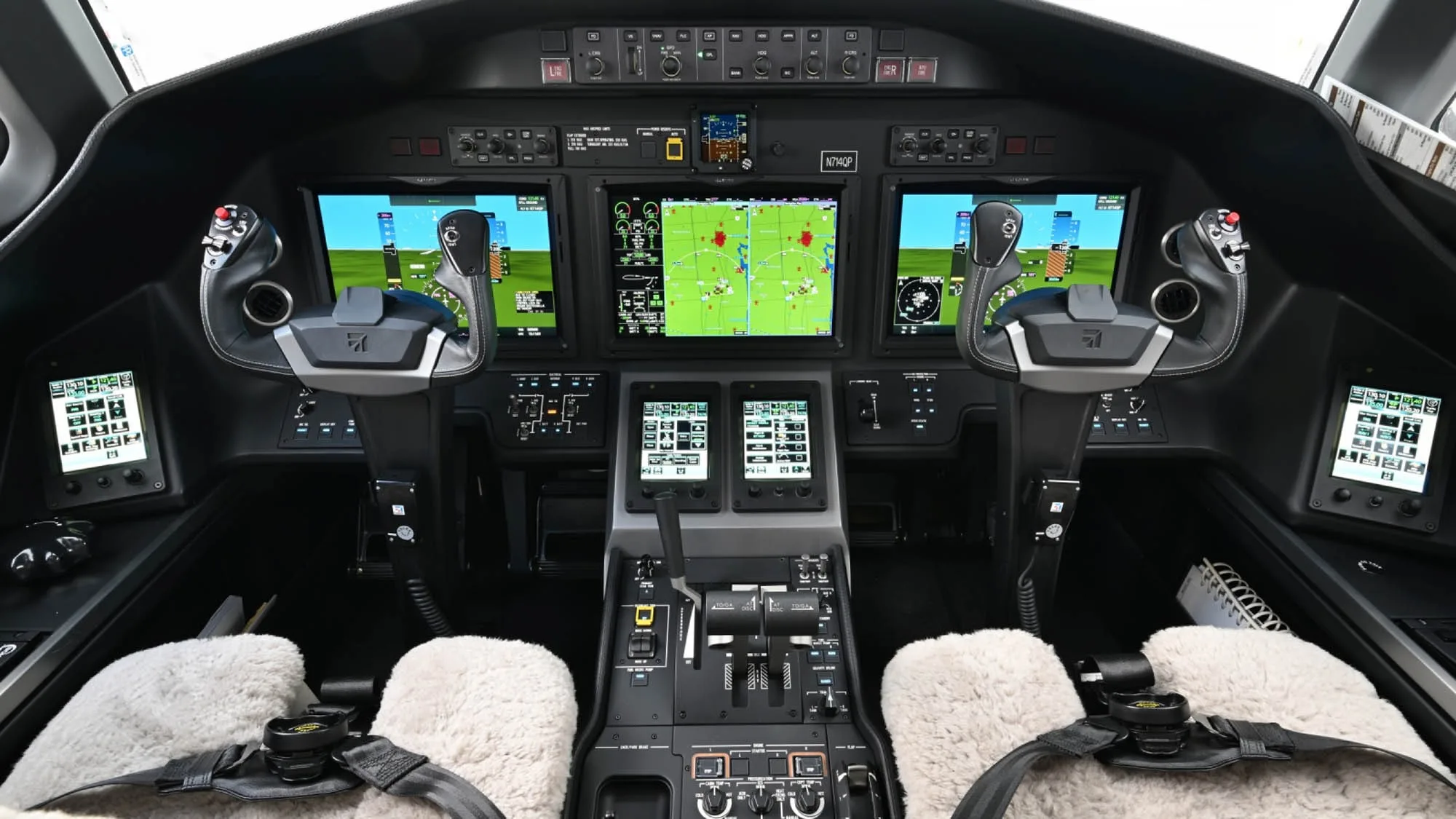 The modern cockpit of a business jet, N714QP, features multiple digital displays and controls.