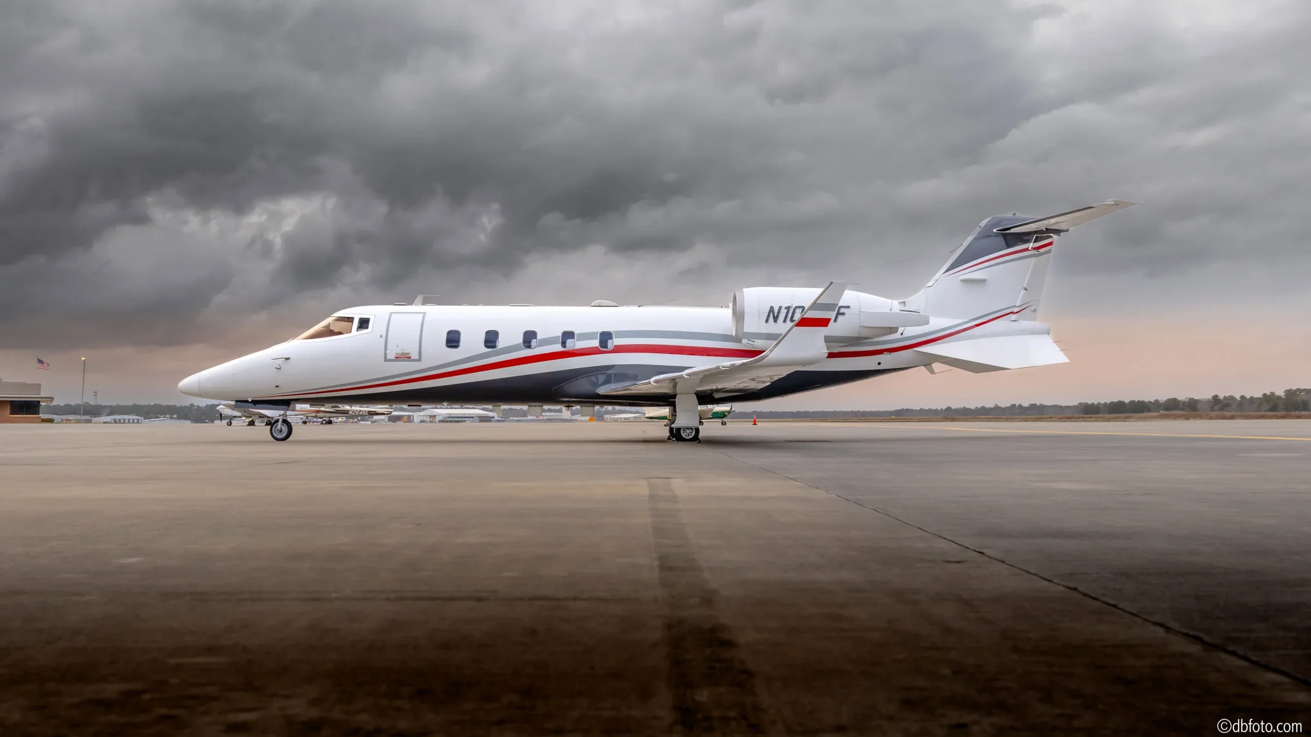 Side view of a Phenom 300 aircraft with registration N10CF on the tarmac.