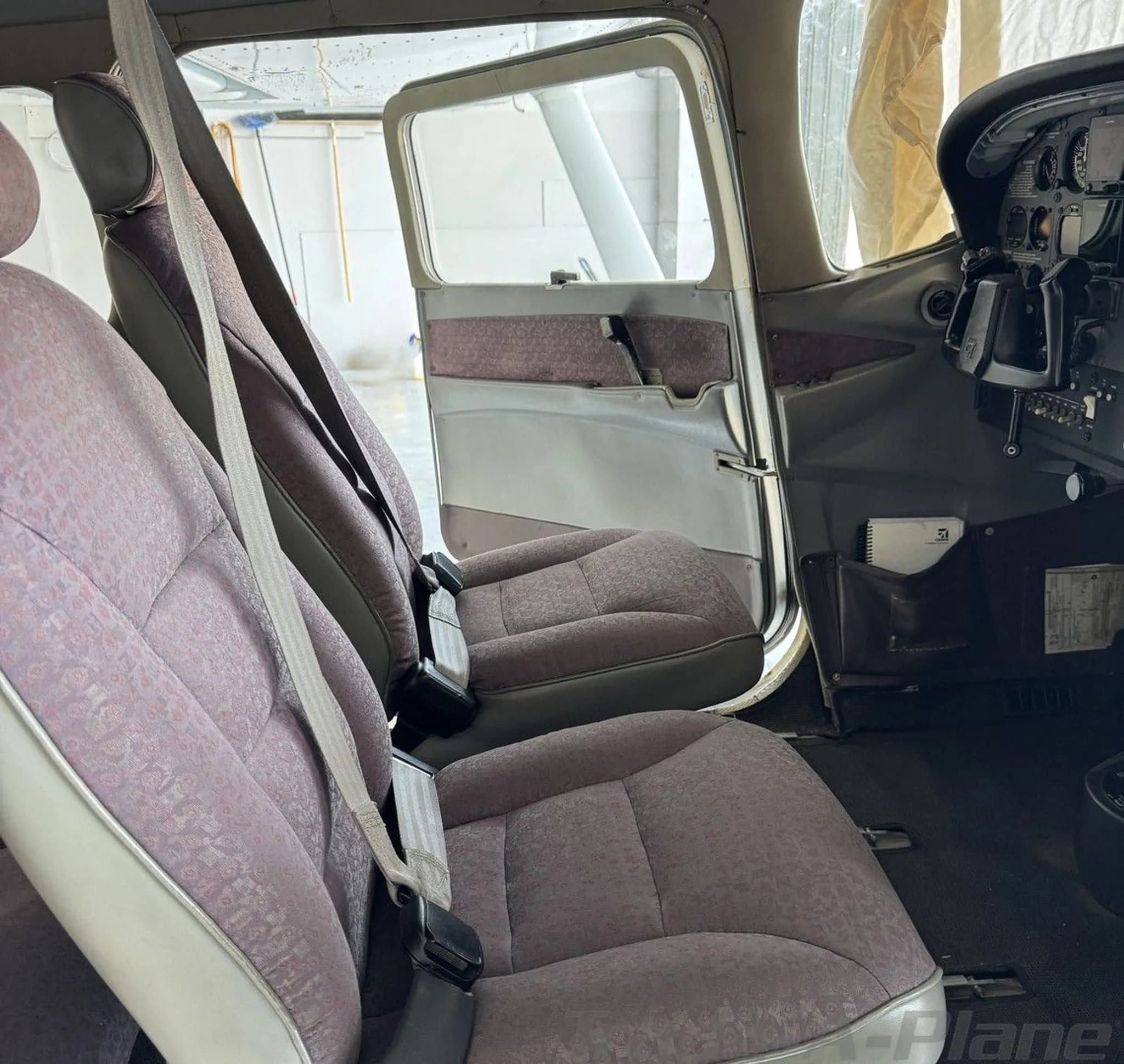 The aircraft's interior, showing the front and rear passenger seats and a glimpse of the cockpit instruments.