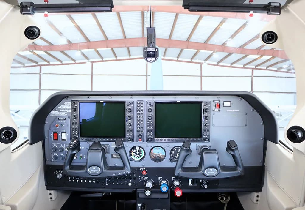 The cockpit features a modern glass panel display with two large screens and dual yokes.