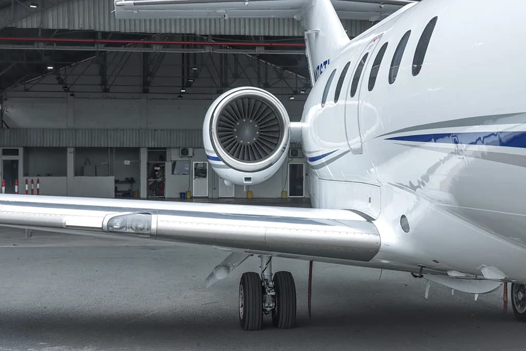 A close-up view of the wing, main landing gear, and rear-mounted engine of a white business jet.