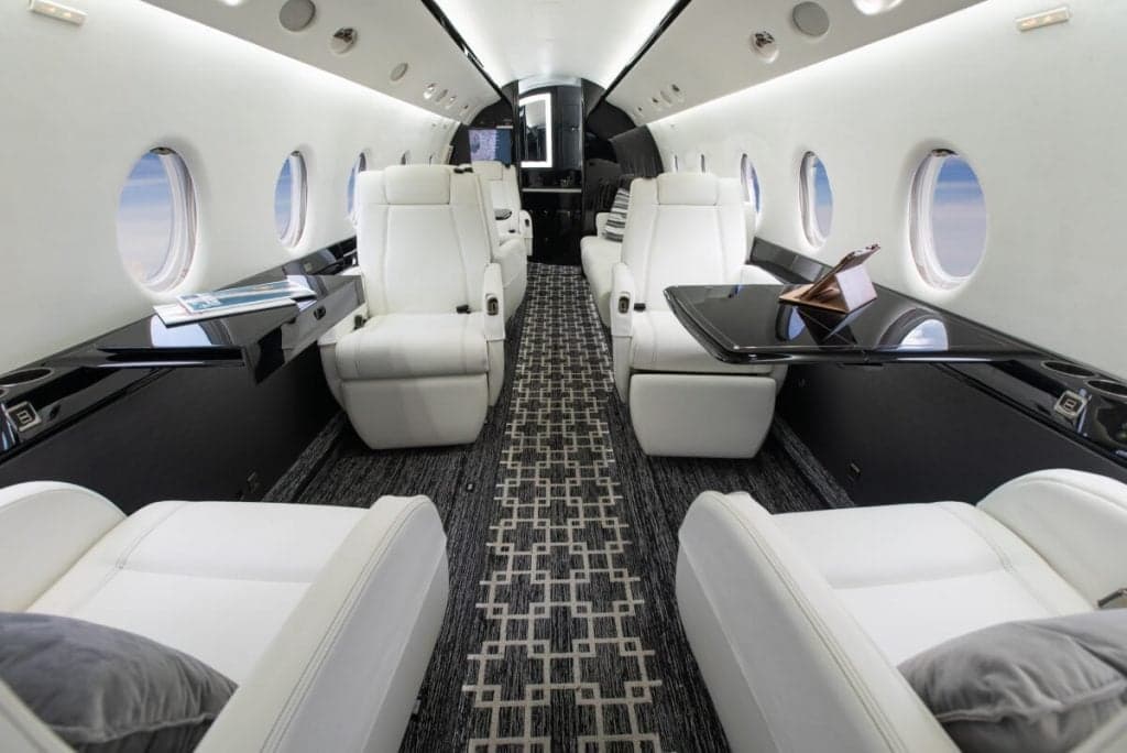 View of the aircraft's interior with white leather seats and black accents.