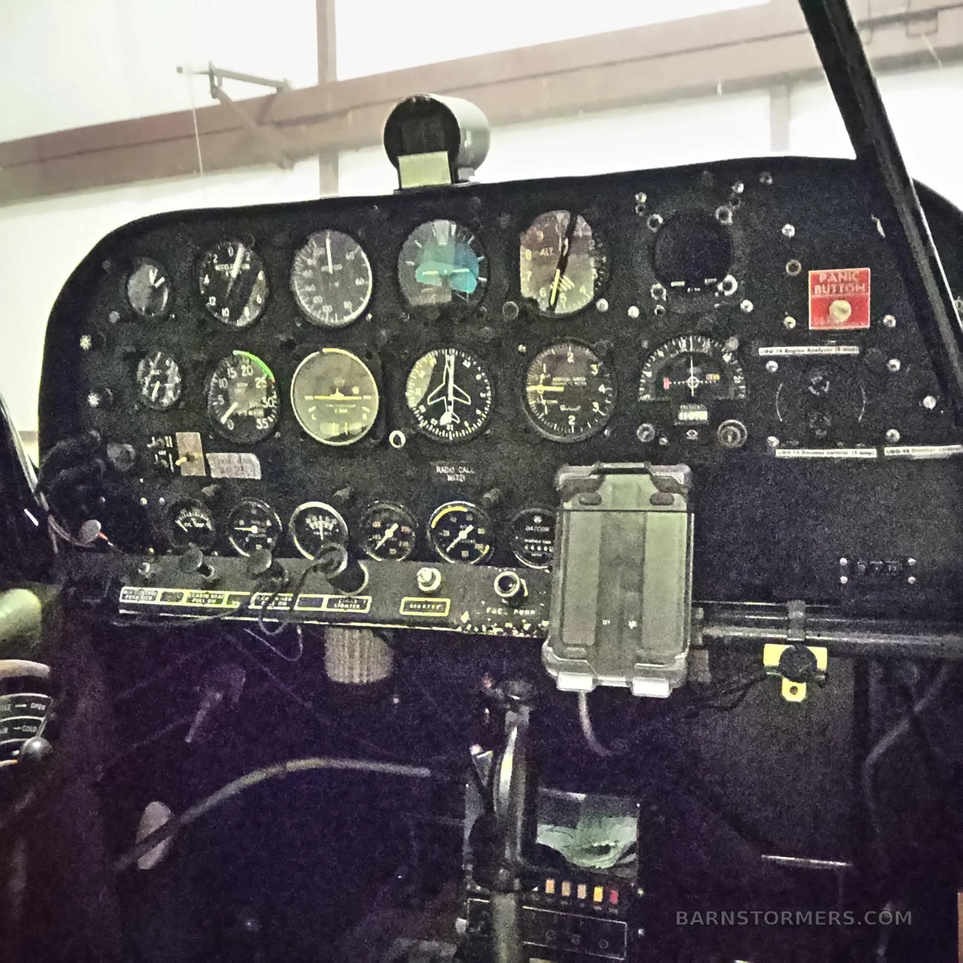 A close-up view of an aircraft cockpit instrument panel with various gauges and a "PANIC BUTTON" label.