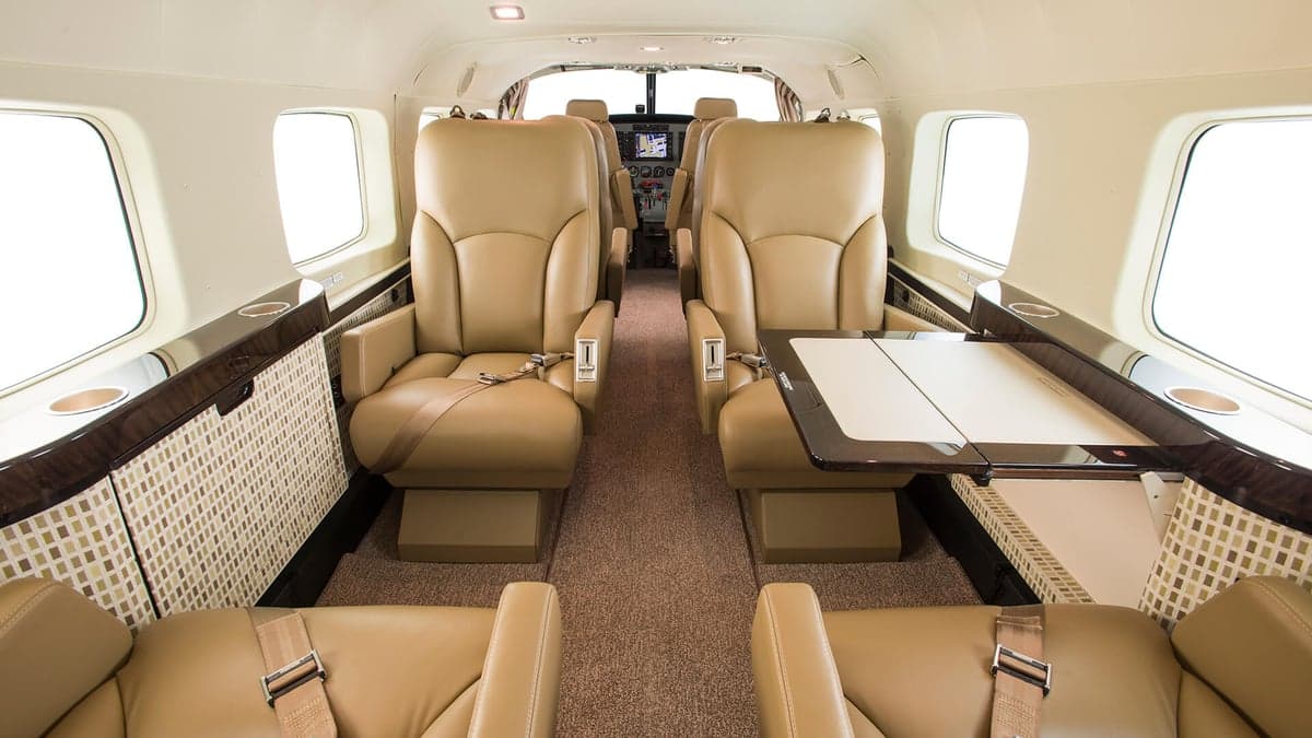 The interior of a Cessna Caravan with tan leather seats and a folding table.
