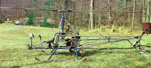 A/W-95 helicopter on a grassy field with trees in the background.