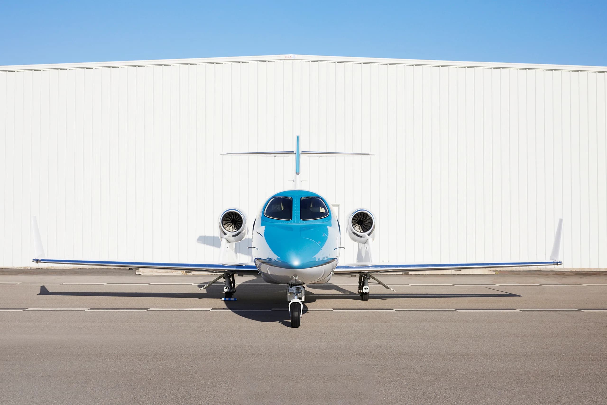 Front view of a HondaJet Elite in front of a hangar.