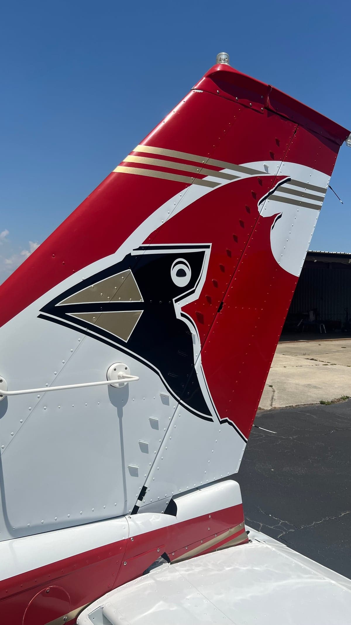 A close-up view of the aircraft's tail, featuring a red and white paint scheme with a black and gold cardinal logo.