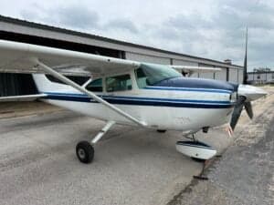A Cessna aircraft with a white and blue paint scheme parked on the tarmac.