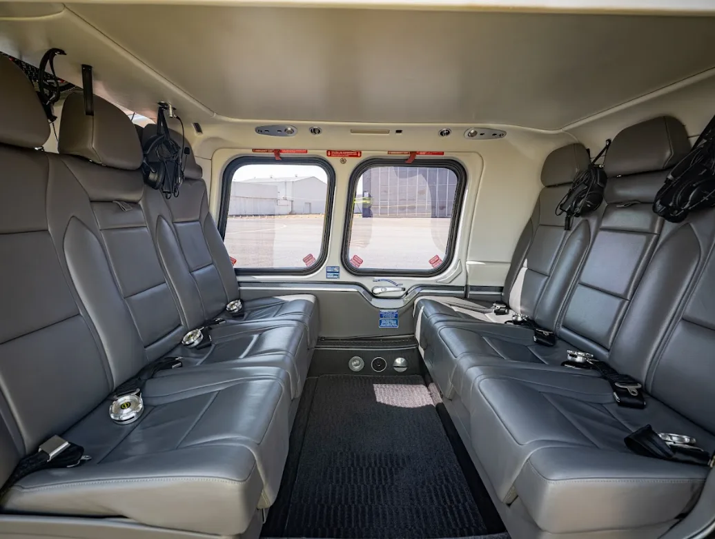 The spacious grey leather interior cabin of an AgustaWestland AW109 GrandNew helicopter with seating for multiple passengers.