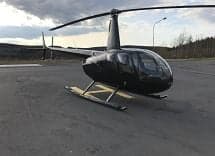 Side view of a black Robinson helicopter on the tarmac.